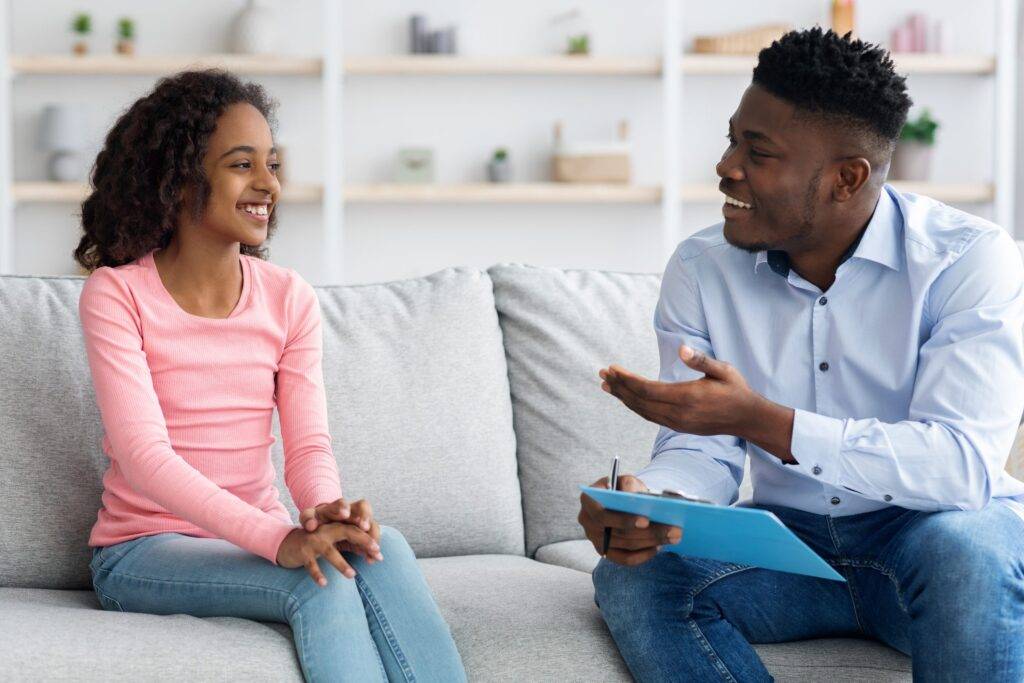Pretty black girl teenager attending therapy session with handsome male psychologist. Paying attention to referrals is also how to find the right therapist.