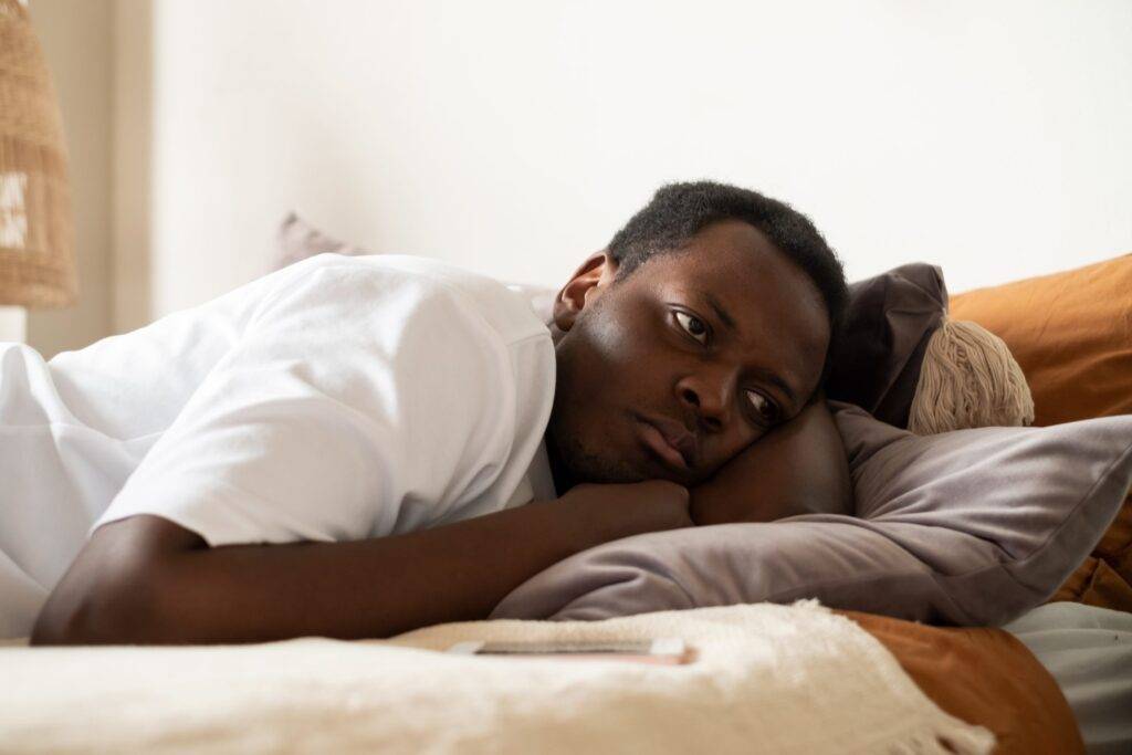 Close-up of lonely african man in bed.