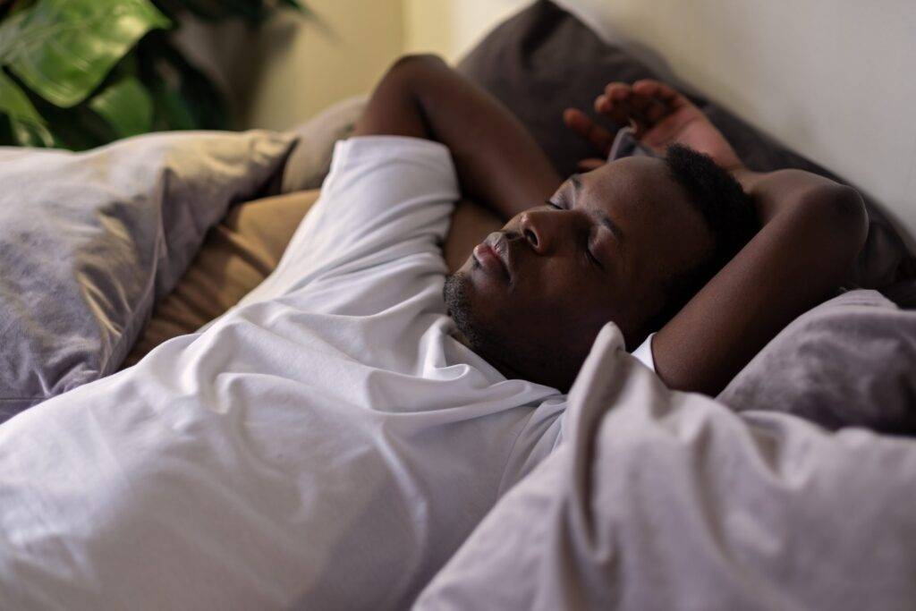 Young handsome african man resting in bed sleeping or napping.