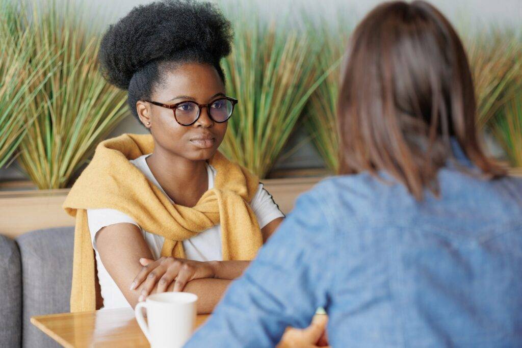 A young lady discussing with a therapist abput PTSD in adults.