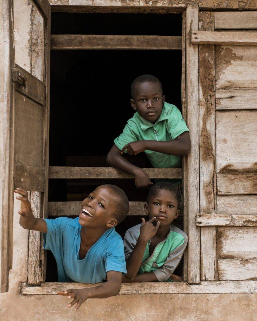 3 young boys smiling at a window