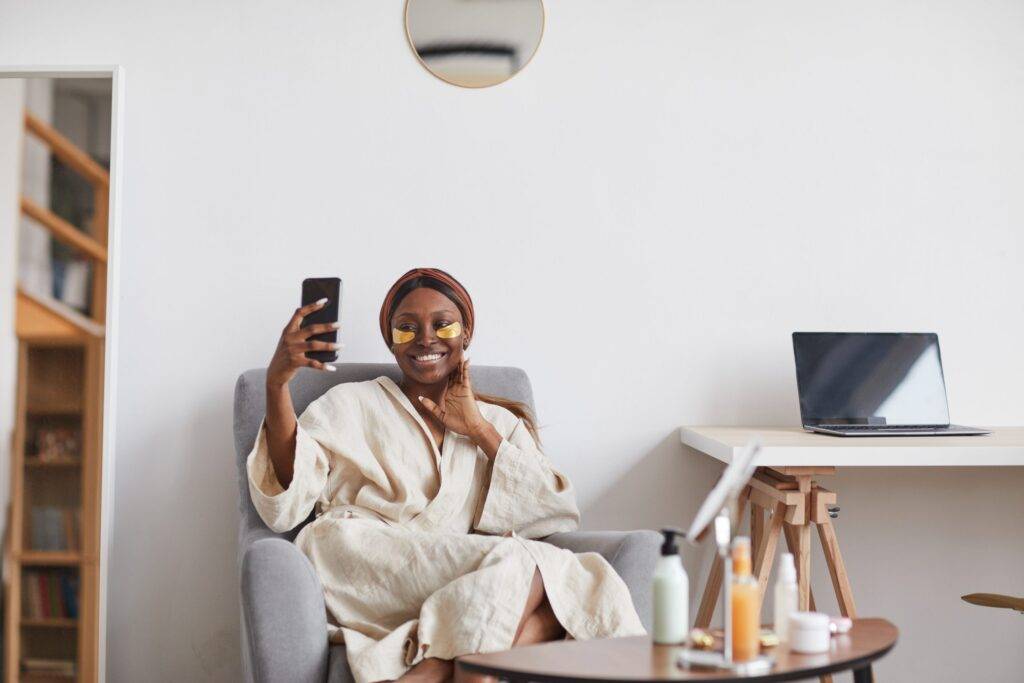 Minimal portrait of beautiful African-American woman enjoying skincare routine at home and taking selfie.